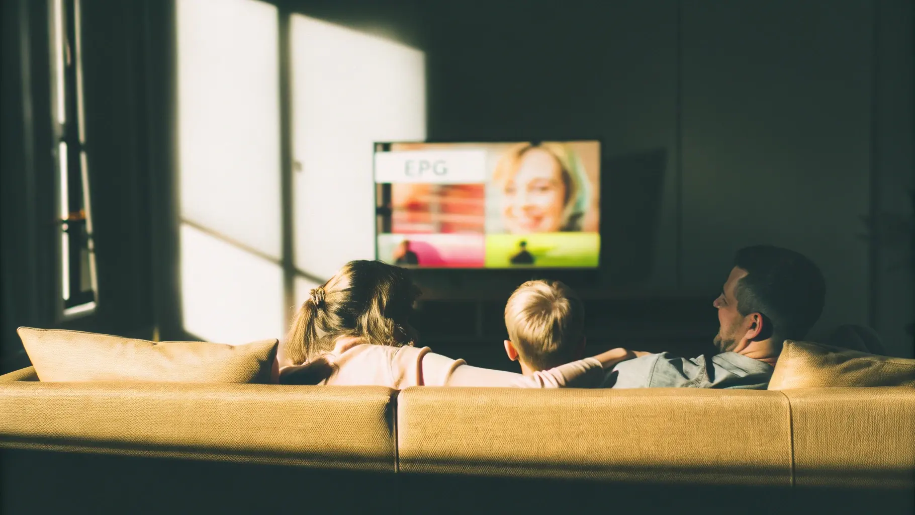 Family on a sofa watching IPTV with the on-screen EPG TV guide